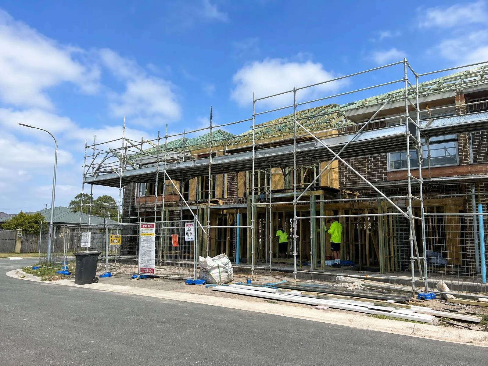 Australian low-rise residential townhouses under construction with scaffolding and roof trusses